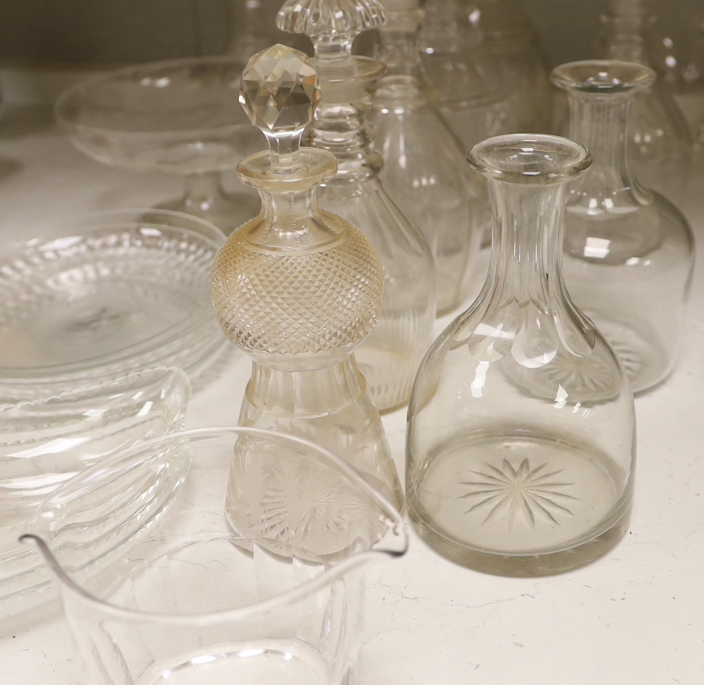 A collection of cut glass decanters and other glassware including five decanters with stoppers, three carafes, two jugs, five shallow round dishes, a pedestal dish, four Crescent dishes and a rinser, tallest 25cm